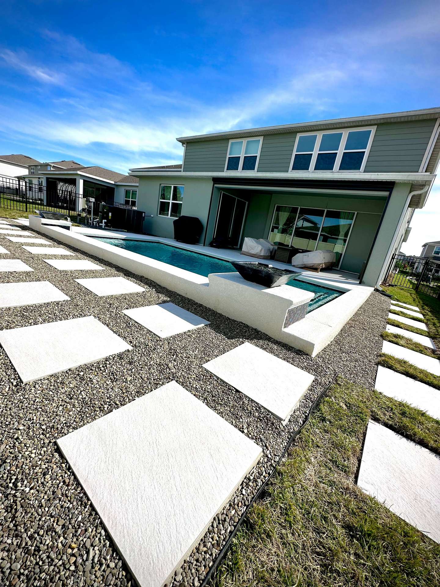 Pavers and stone in the back yard behind a pool